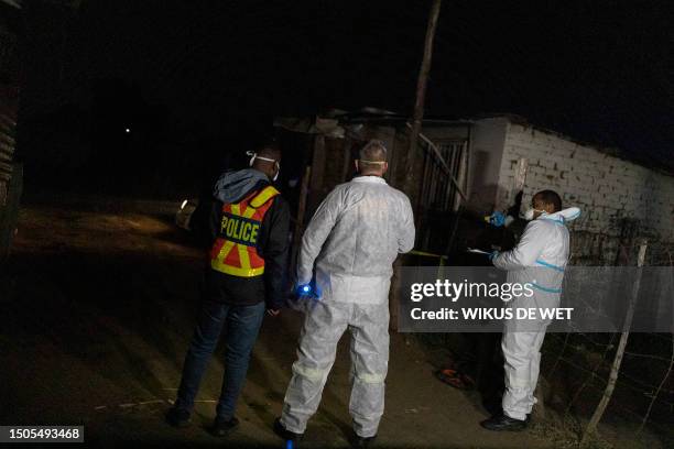 Members of the South African Police Service's forensic department take measurements about 300 metres away from a scene where people died from a gas...