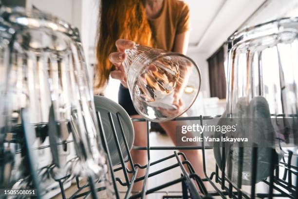 a woman is emplying the dishwasher - spülmaschine stock-fotos und bilder