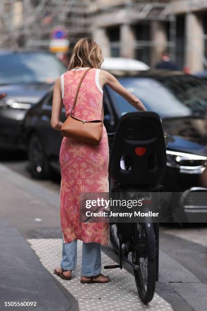 Guest is seen wearing black sunglasses, a red orange and white knitted dress with flower print and a flared blue jeans combined with brown sandals...