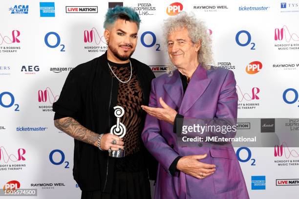Adam Lambert poses in the winners room with the International Award alongside Brian May during the Nordoff and Robbins O2 Silver Clef Awards 2023 at...