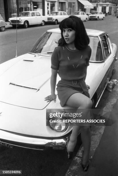 La romancière vietnamienne Mei Chen Chalais assise sur une voiture ancienne à Paris le 10 novembre 1967