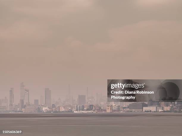 long exposure of hudson yards and midtown manhattan across the hudson river on a hazy day where the canadian fire smoke engulfs the city including the empire state building and the chrysler building - engulfs stock pictures, royalty-free photos & images