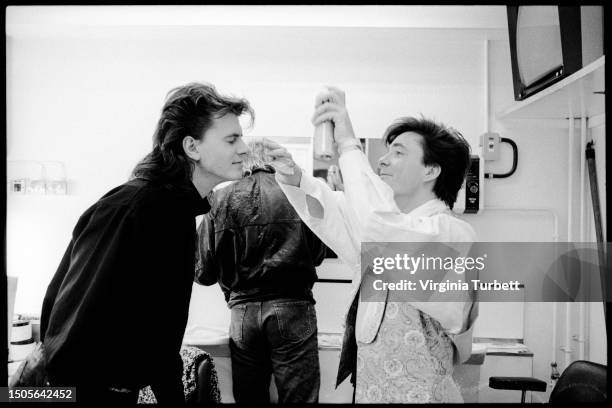 John Taylor, Simon Le Bon of Duran Duran and Jon Keeble of Spandau Ballet apply hairspray while getting ready in their dressing room before a...