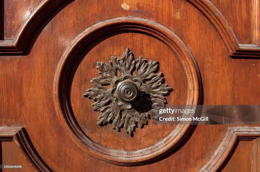 Ornate floral door knob on a wooden door with border trim