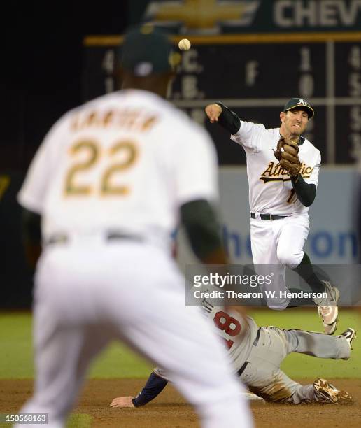 Adam Rosales of the Oakland Athletics gets his throw off to Chris Carter at first base to complete a triple play while avoiding the slide of Ryan...