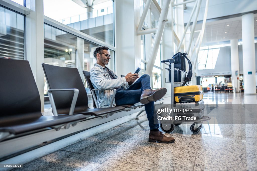 Mature man using mobile phone in waiting room at the airport