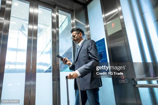 homme d’affaires utilisant un téléphone portable à l’intérieur de l’ascenseur - elevator stock photos et images de collection