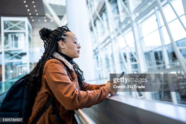 young woman using phone at the airport - braiding hair stock pictures, royalty-free photos & images