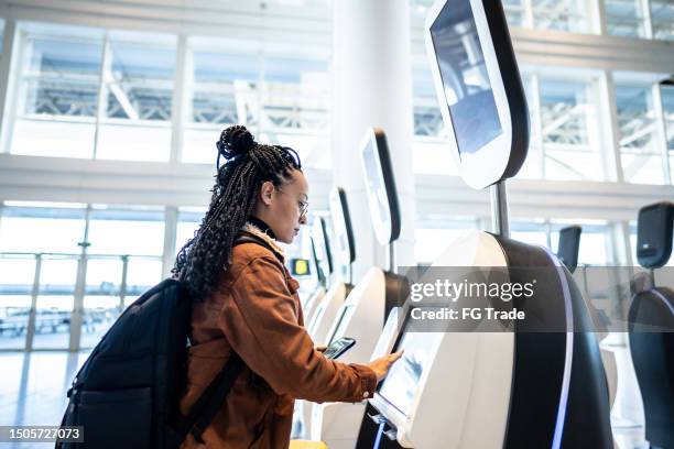 young woman using self service check-in machine at the airport - braiding hair stock pictures, royalty-free photos & images