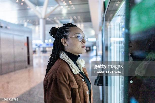 young woman looking at vending machine at the airport - self service stock pictures, royalty-free photos & images