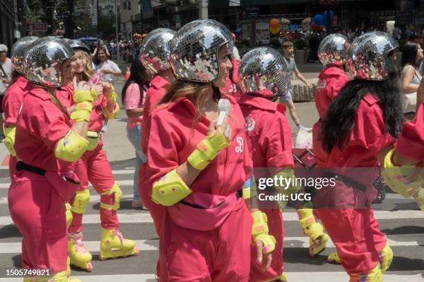 People wearing pink jumpsuits, silver mirrorball-like helmets, bright yellow custom inline skates and pads on their wrists, elbows, and knees, wait...