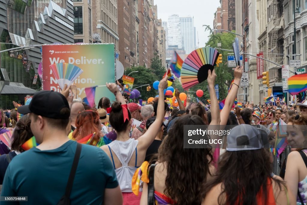 Spectators and participants waving fans and flags are jam-packed, NYC Pride March 2023