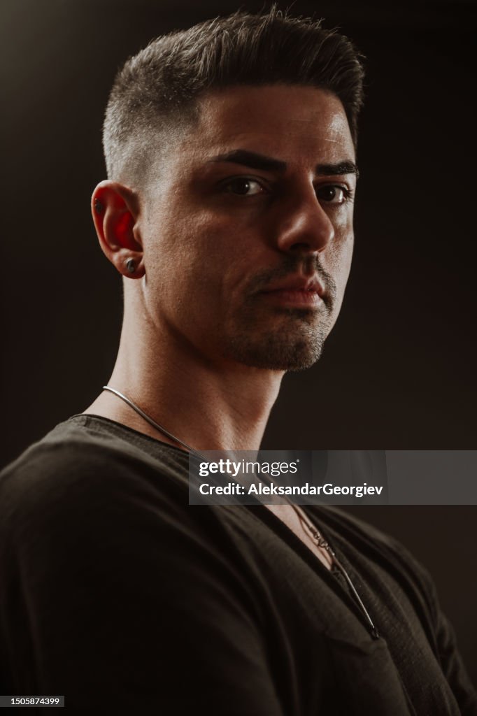 Macho bonito mostrando seus olhares piercing no fundo preto