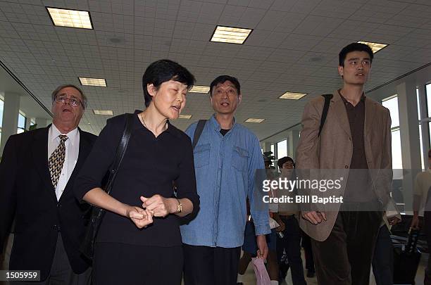 Yao Ming of the Houston Rockets is escorted through Houston Intercontinental Airport by Carroll Dawson, Rockets General Manager, his mother, Fang...