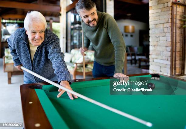 senior man and his son playing a pool game together at home - billiard ball game stockfoto's en -beelden