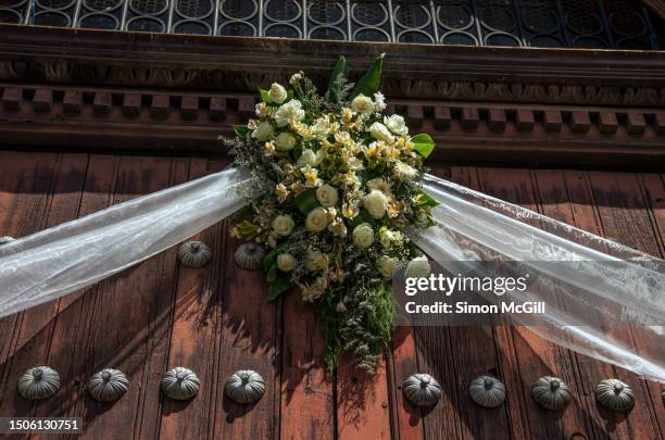 wedding floral arrangement hanging above the double doorway to an old church - organdy stockfoto's en -beelden