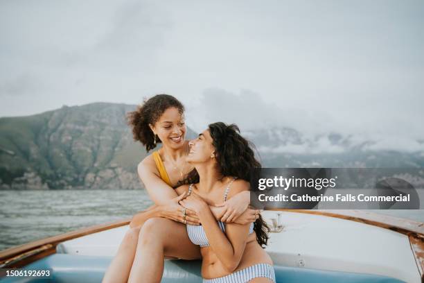 two woman embrace during a romantic boat ride - honeymoon stock pictures, royalty-free photos & images