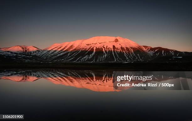 scenic view of lake by snowcapped mountains against sky during sunset,castelluccio di norcia,italy - andrea rizzi 個照片及圖片檔