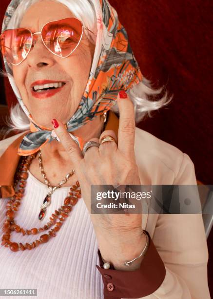 senior woman rock and roll hand sign - coole oma stock-fotos und bilder