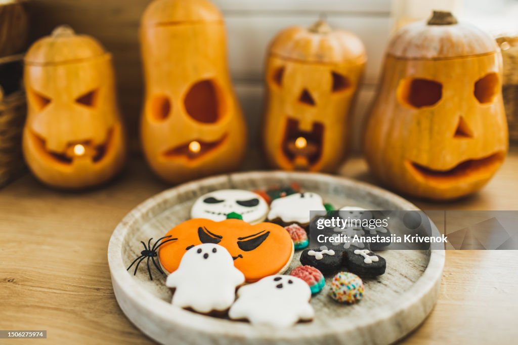 Halloween background with spooky ghost shaped cookies on tray and pumpkin lanterns