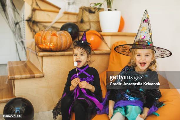 two naughty sister girls laughing and having fun on kids halloween party. sweet childhood - naughty halloween photos et images de collection