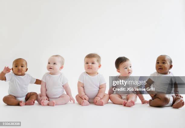 babies sitting on floor together - baby group stockfoto's en -beelden