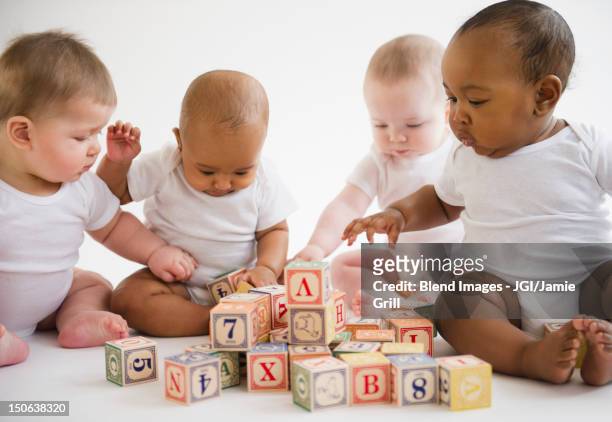 babies sitting on floor playing with blocks - four people stock pictures, royalty-free photos & images