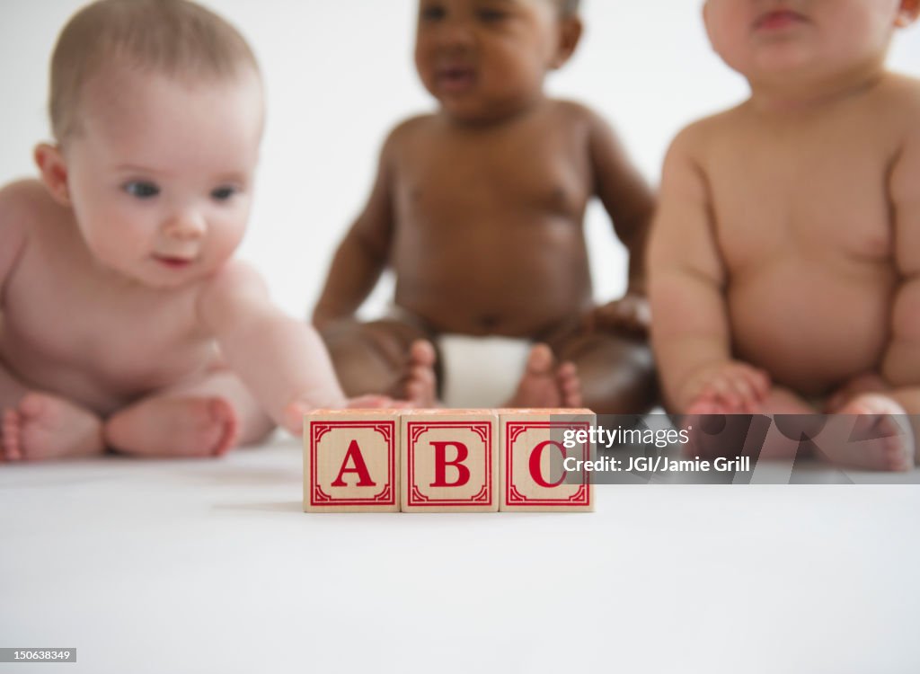 Babies sitting with alphabet blocks
