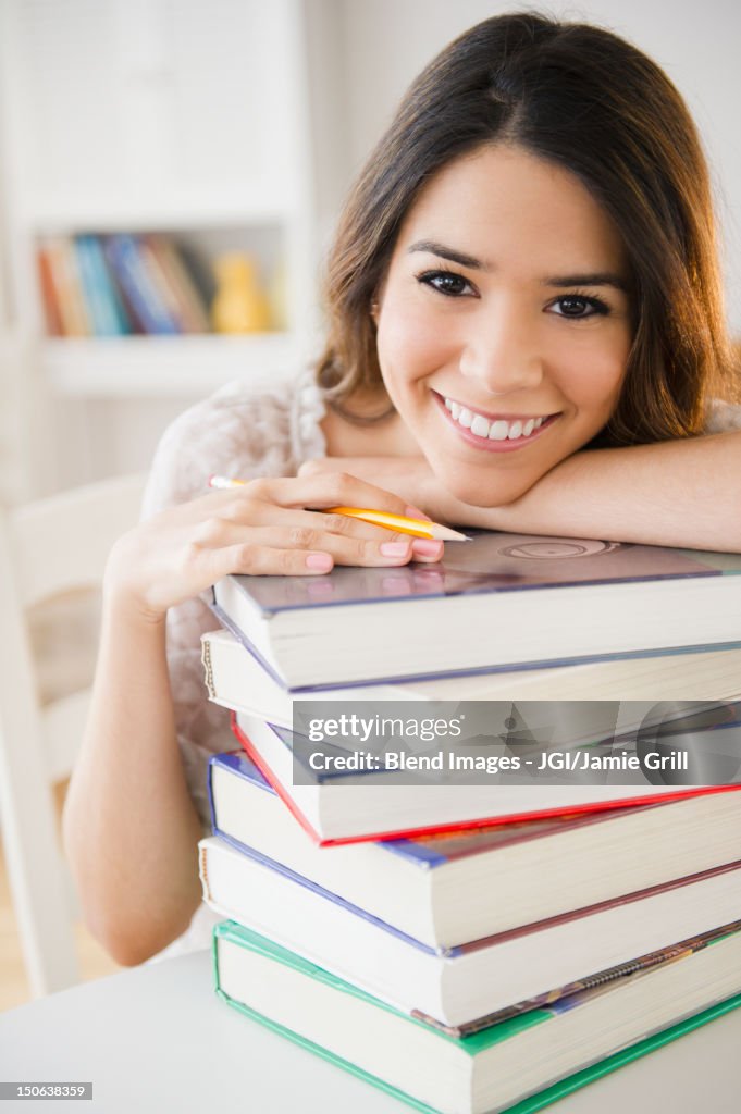 Hispanic student leaning on stack of books