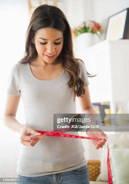 hispanic woman measuring waistline - measure waist stock pictures, royalty-free photos & images