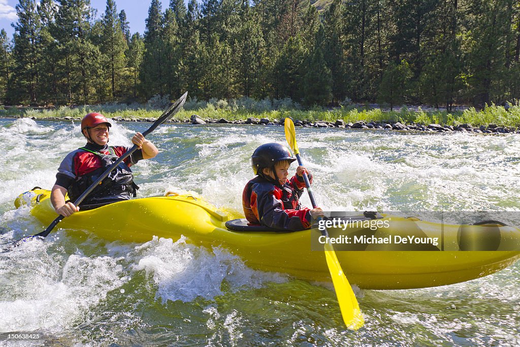 Caucasian father and son kayaking in river