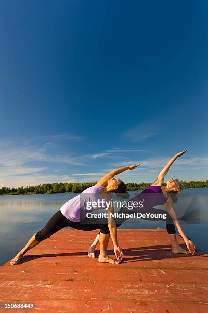 women stretching on lake pier - equal arm balance stock-fotos und bilder