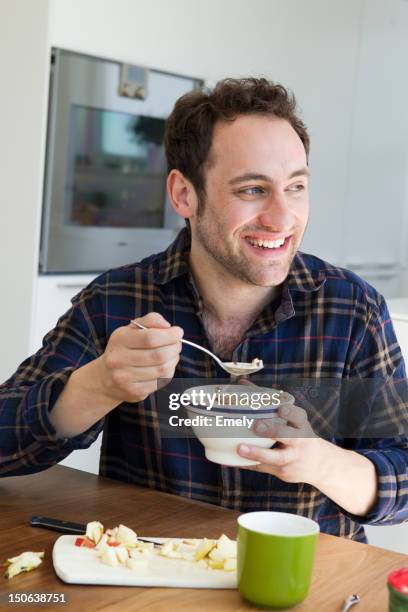 smiling man eating bowl of cereal - adult eating cereal stock pictures, royalty-free photos & images