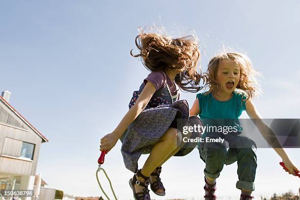 girls jumping rope together outdoors - seilspringen stock-fotos und bilder
