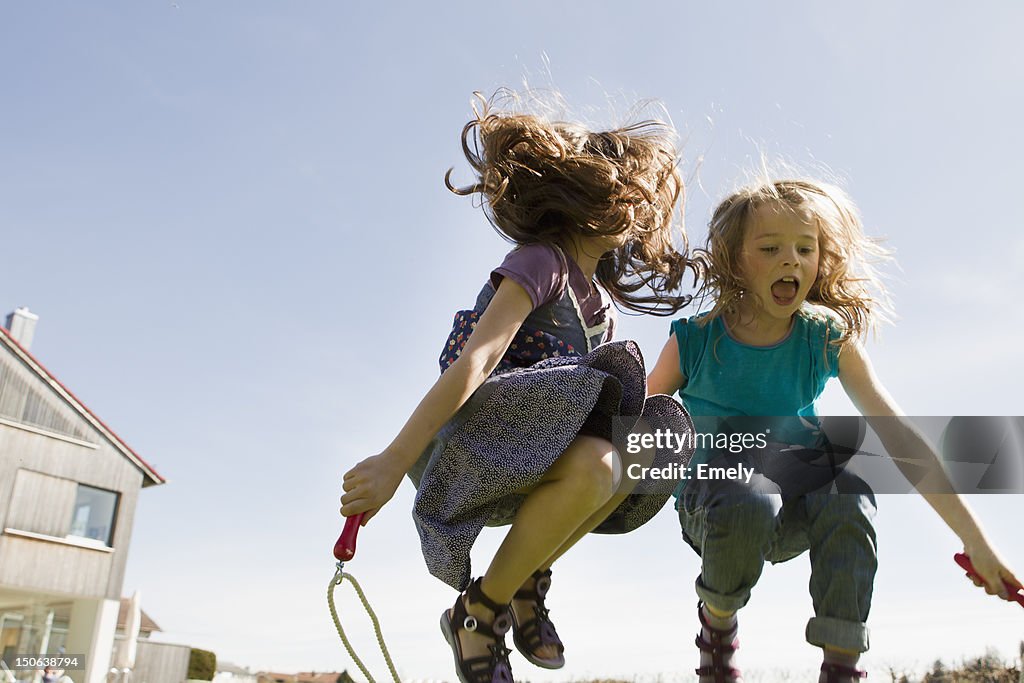 Girls jumping rope together outdoors