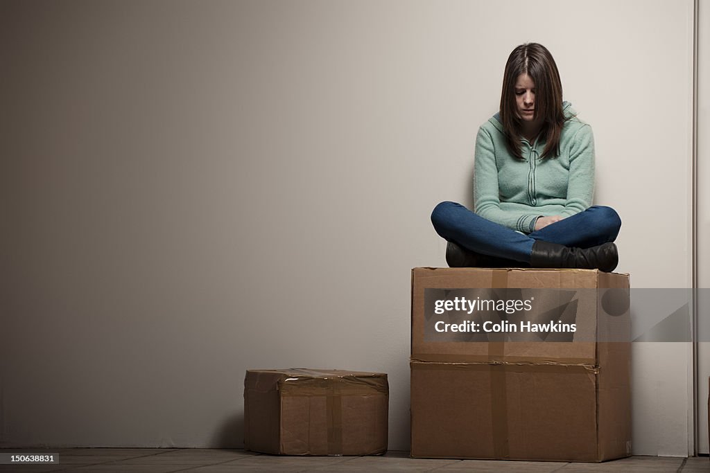 Teenage girl sitting on cardboard box