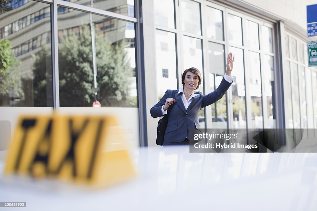 Businesswoman hailing taxi on street