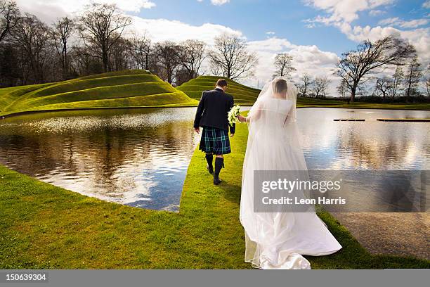 newlywed couple walking on grassy bridge - wedding lake stock pictures, royalty-free photos & images