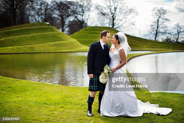 newlywed couple kissing in field - kilt stock pictures, royalty-free photos & images