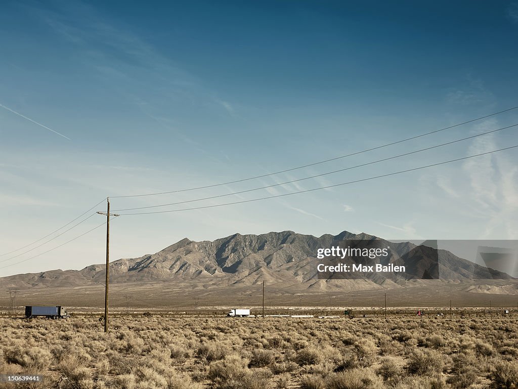Power lines, dirt road and mountain