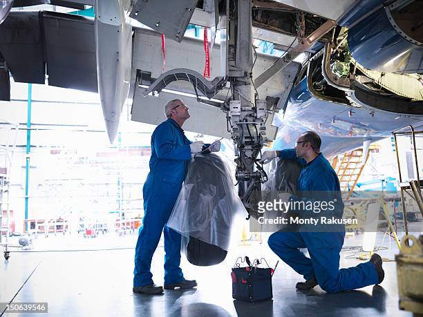 aircraft engineers working on undercarriage area and landing gear of 737 jet plane - airplane part fotografías e imágenes de stock