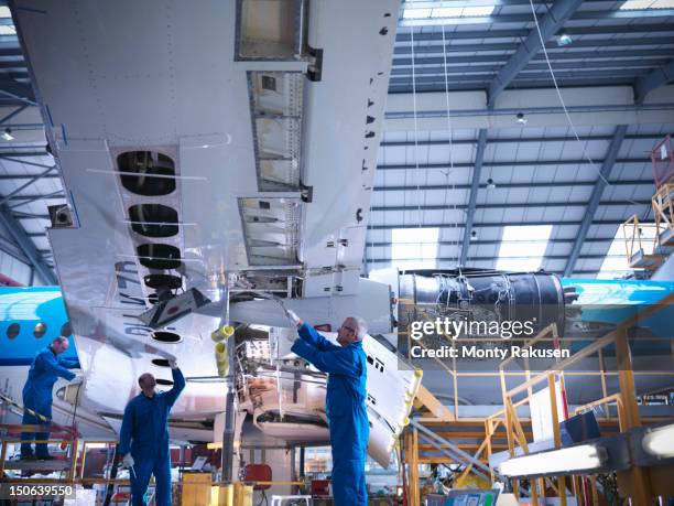 aircraft engineers working on underside of wing of 737 jet plane - aircraft assembly plant stock pictures, royalty-free photos & images