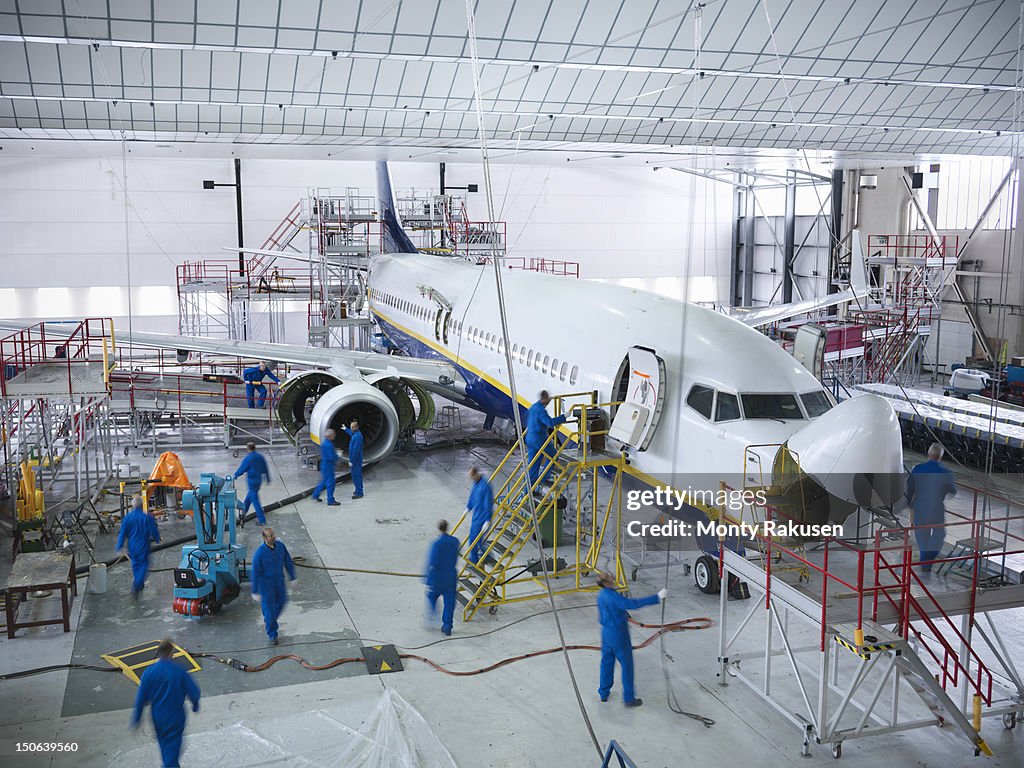 Engineers working with aircraft in repair hangar