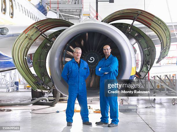 portrait of aircraft engineers in front of 737 engine in hangar - blaumann stock-fotos und bilder