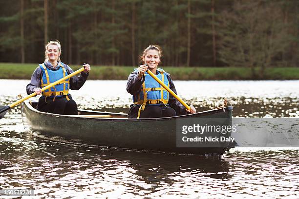 women rowing canoe on still lake - two people canoeing on a lake stock pictures, royalty-free photos & images