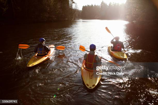 kayakers rowing together on still lake - kayaking stock pictures, royalty-free photos & images