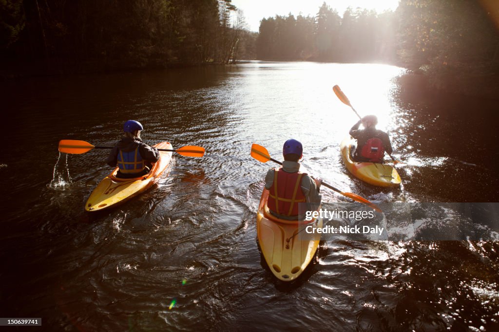 Kayakers rowing together on still lake