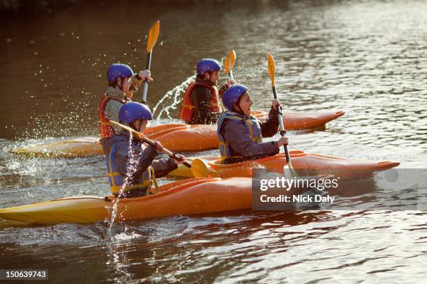 kayakers rowing together on still lake - canoe stock pictures, royalty-free photos & images