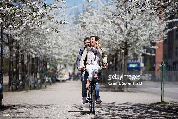 man riding with girlfriend on bicycle - springtime stockfoto's en -beelden