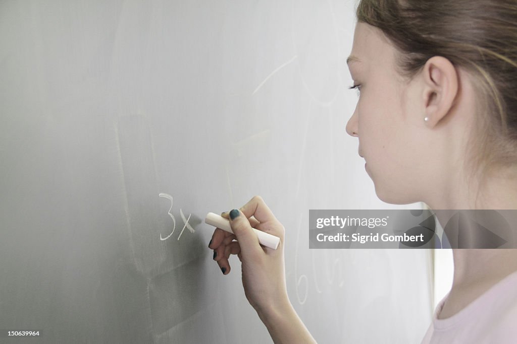 Student writing math on chalkboard